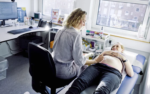 Praktiserende læger undersøger gravid patient med ultralydsscanning.