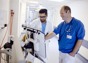 To smilende overlæger der gør brug af en af hospitalets maskiner  